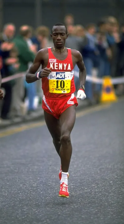 Wakiihuri racing the London Marathon in a red Kenya vest, bib 10, wearing his white racing gloves