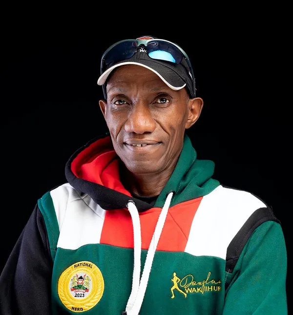 Portrait of Wakiihuri in a Kenya-colours hoodie with the 2023 National Hero badge, on black